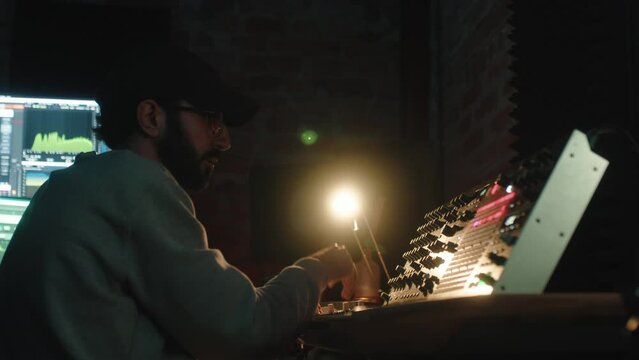 close up of music producer working on synthesizer