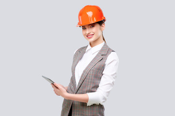 Caucasian succesful woman engineer wearing protection helmet and holding tablet computer isolate on grey background