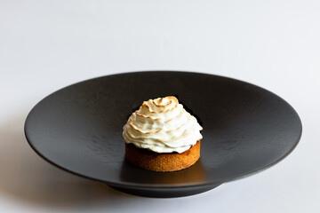 Сake with white cream on a black plate