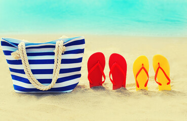 Summer vacation concept - bag and flip flops on beach over blue sea background