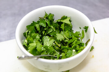 Chopped parsley lies in a white bowl on the table