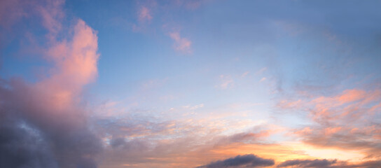 Fototapeta premium blue sky background, framed with pink yellow and orange clouds, sunset scenery