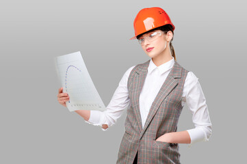 Woman engineer in protective orange helmet wearing glasses holding graph studio on gray isolated background