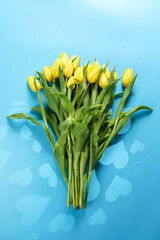 A bouquet of yellow tulips on a blue background with heart-shaped shadows