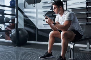 Checking out the latest fitness apps. Shot of a sporty young man using a cellphone in a gym.