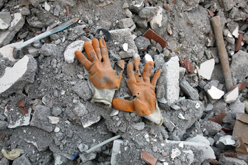 Worn work gloves on construction rubble or waste. Hard-working. 