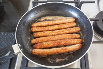 Sausages grilling in a frying pan