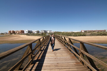 Fototapeta premium A red-haired Caucasian woman on a wooden walkway, on the beach of Isla Cristina, Huelva, Spain.