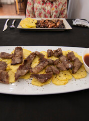 A dish with Iberian pork meat called (Pluma), accompanied with potatoes.