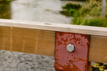 A metal bolt secures the metal docking of the wooden handrail.