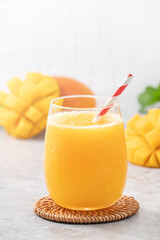 Fresh beautiful delicious mango juice smoothie in a glass cup on gray table background.