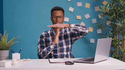 Portrait of employee showing timeout gesture and looking at camera, expressing wish to take break and pause from work. Overworked man asking for half time, to control limits finish.