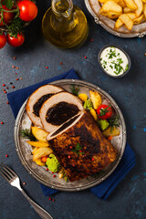 Whole roasted pork loin stuffed with dried plum. Top view. Dark blue background.