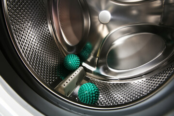 Green dryer balls in washing machine drum, closeup