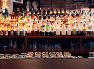 Empty bar counter with blurry liquor bottles on the shelves. Background backdrop use.