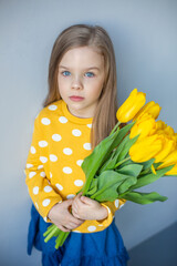 Happy adorable girl with yellow fresh bouquet of tulips. Childhood,  flowers concept