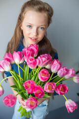 Happy adorable girl with pink fresh bouquet of tulips. Childhood,  flowers concept