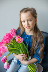 Happy adorable girl with pink fresh bouquet of tulips. Childhood,  flowers concept