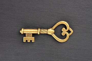 Bronze vintage antique key on black wooden background. Concept of antiques