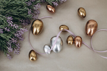 Small golden and silver eggs laying by the flowers