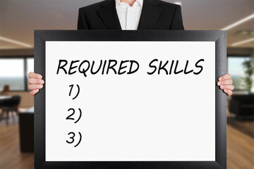Businessman holds a big signboard with required skills message.