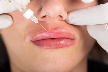 Young lady getting injections for bigger, fuller lips. The woman in the beauty salon. Plastic...