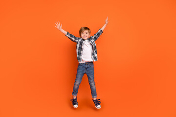 Full length photo of young cheerful boy have fun jump up wear modern outfit isolated over orange color background - obrazy, fototapety, plakaty