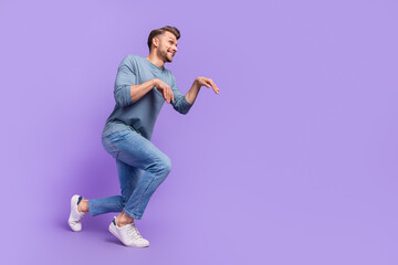 Fototapeta na wymiar Full size photo of funky brown hairdo guy go wear shirt jeans sneakers isolated on violet color background
