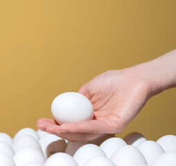 hand takes a white egg from the tray. Background for text Holiday Easter