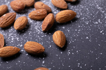 Extreme close-up of nutritious almonds with salt on black background