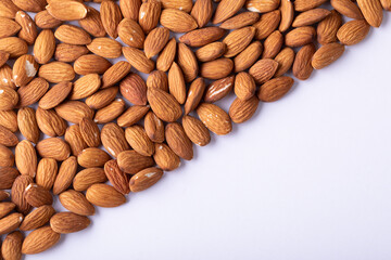 High angle view of fresh nutritious almonds arranged in diagonal on white background with copy space