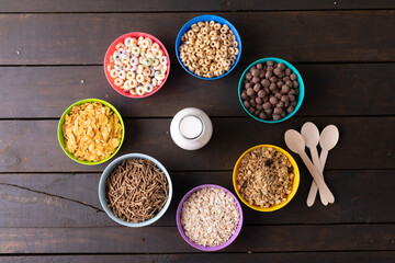 Directly above shot of various breakfast cereals arranged in bowls around milk bottle on table