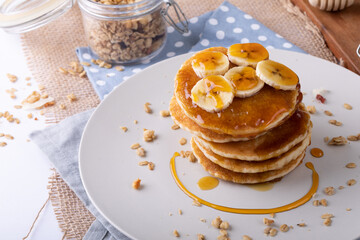 High angle view of pancakes served with banana slices, oats and honey in plate on napkin