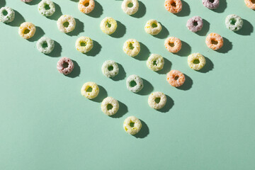 Overhead view of colorful ring shaped breakfast cereal arranged on green background