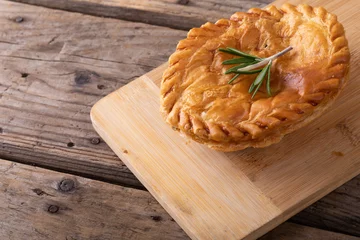 Poster Close-up of baked stuffed pie with rosemary on wooden serving board at table © WavebreakMediaMicro