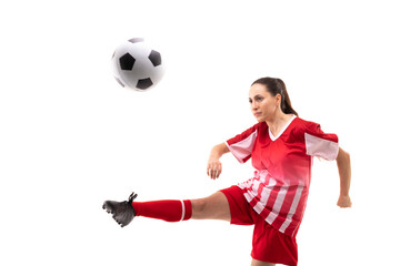 Full length caucasian young female player kicking ball while playing soccer against white background