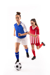 Fototapeta na wymiar Full length of biracial and caucasian young female players playing soccer against white background