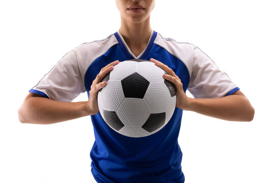 Midsection of biracial young female soccer player holding soccer ball against white background