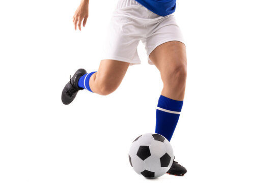 Low section of biracial young female soccer player kicking soccer ball against white background