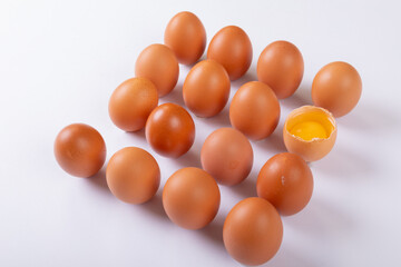 High angle view of brown eggs with one broken egg arranged in square on table