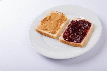 High angle view of open face peanut butter and jelly sandwich in plate on white background