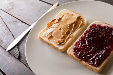 Close-up of preserves and peanut butter on bread slices served in plate at table with table knife