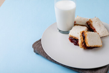High angle view of peanut butter and jelly sandwich slices served with milk glass in plate on table
