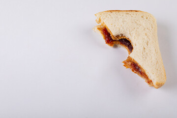 Close-up of missing bite on peanut butter and jelly sandwich over white background with copy space