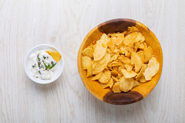 Directly above shot of white dipping sauce with herbs served by potato chips in bowl on table
