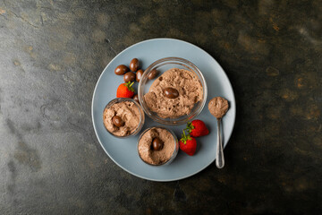 Overhead view of chocolate mousse with coated nuts and strawberries served in plate at table