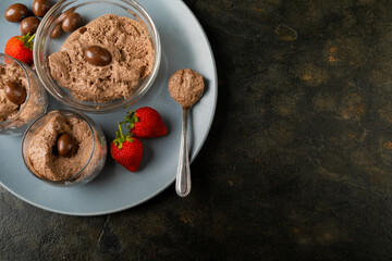 Directly above shot of chocolate mousse with coated nuts and strawberries served in plate at table