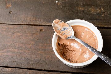 Chocolate mousse served in ramekin bowl with spoon on table with blank space