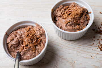 Close-up of chocolate mousse with cocoa powder served in ramekin bowls on table