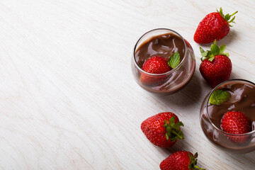 Strawberries and mint leaves with chocolate dessert served in bowls on table with empty space
